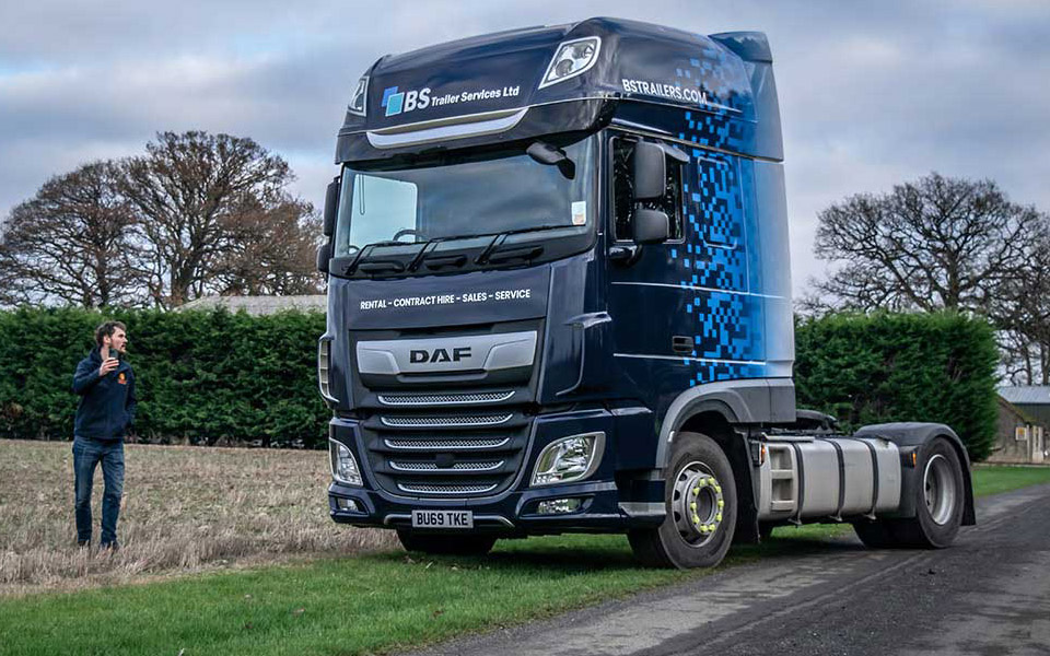 A DAF HGV tractor-unit wrapped for BS Trailer Services Ltd, featuring a dark blue frontage transitioning to a lighter blue, via a pixelated effect.