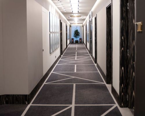A long hallway featuring a striking black and white carpet pattern, creating a visually dynamic and elegant atmosphere.  