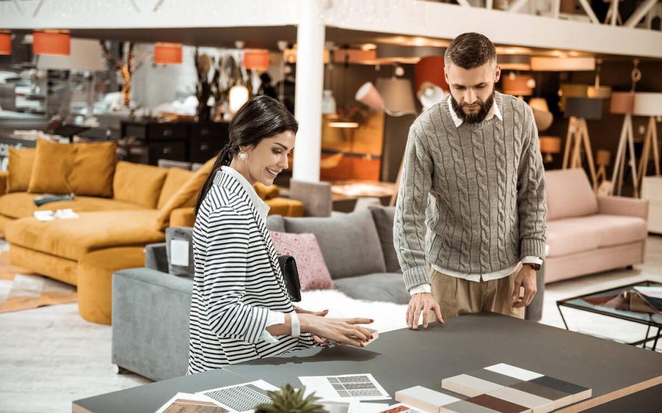 bearded man showing his wife wooden pieces and discussing color table surfaces