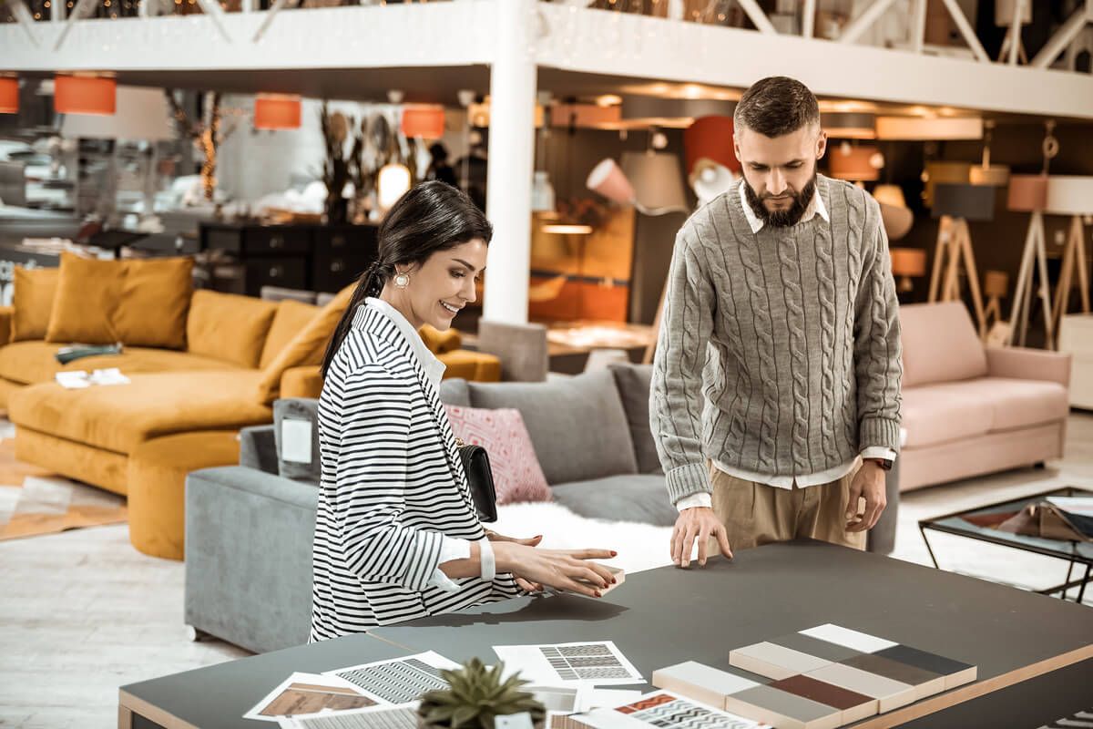 bearded man showing his wife wooden pieces and discussing color table surfaces