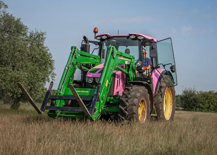 A John Deer tractor from Wallingford, Oxfordshire, wrapped in vibrant pink with green lifting arms