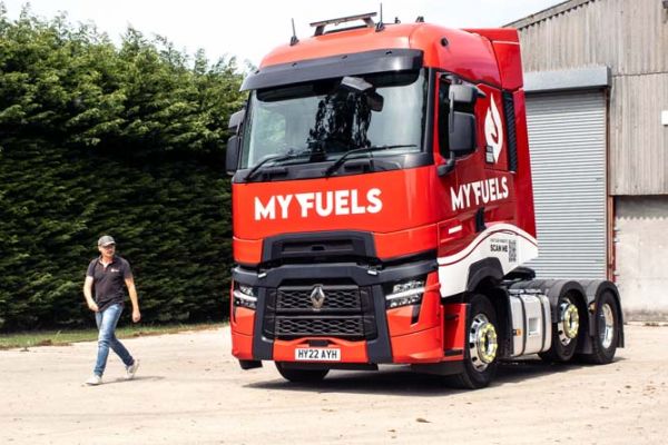 A man strides past a red and white truck parked on the street.